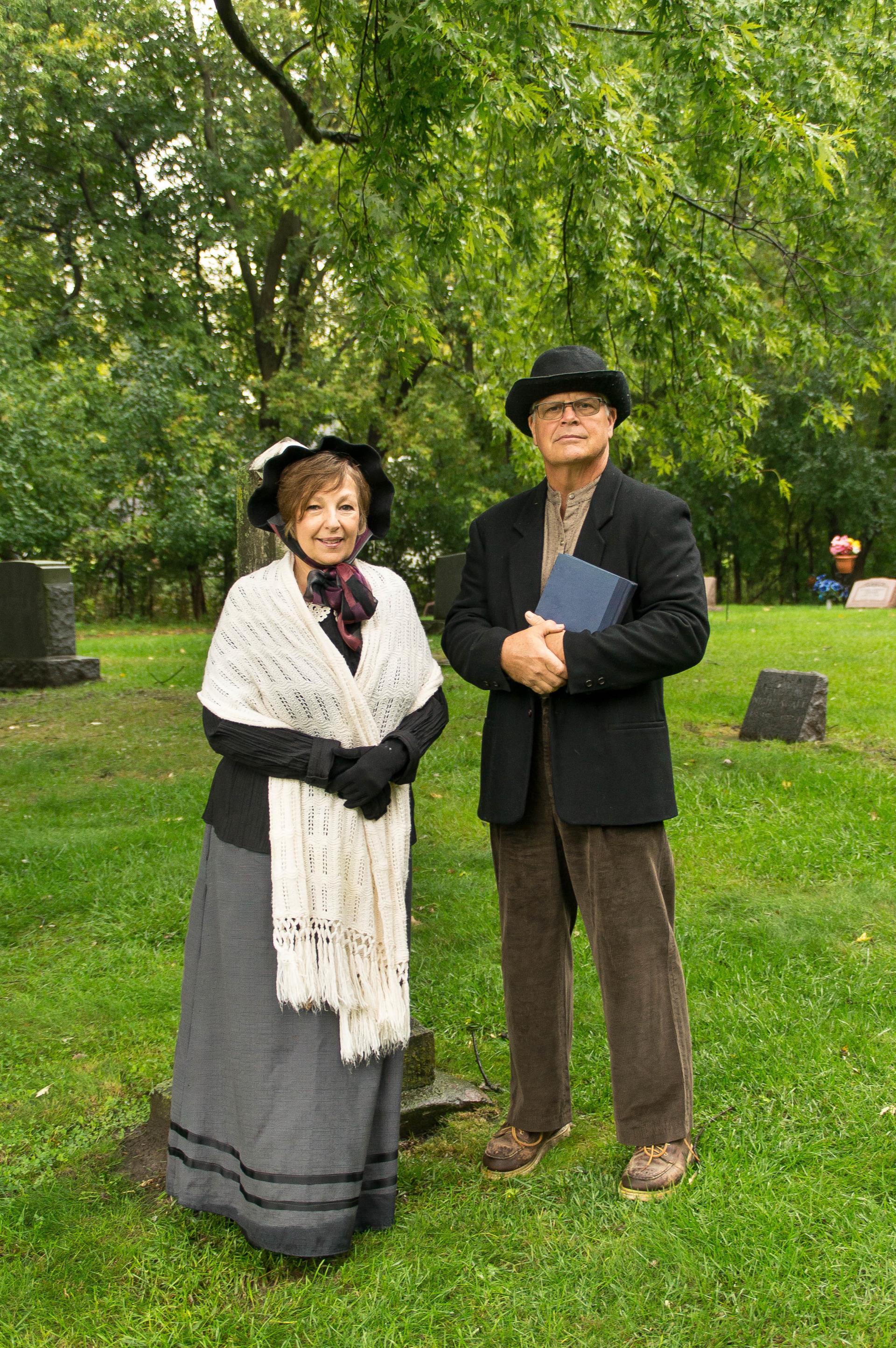 A pair of actors in old-time clothing smile for the camera.